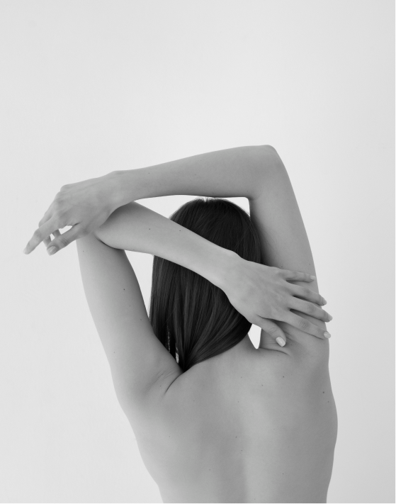 Back view of a woman stretching her arms, highlighting muscle tension relief through massage.