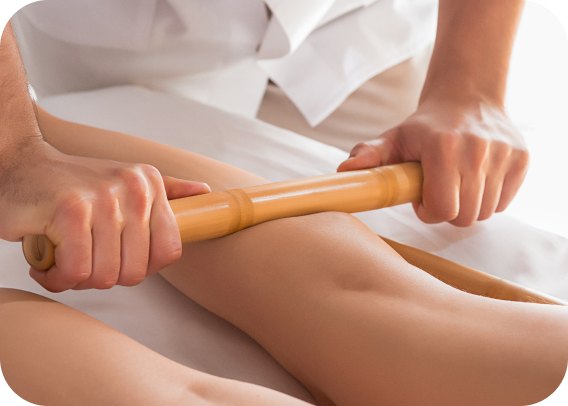 Hands performing a wood therapy massage on a leg.