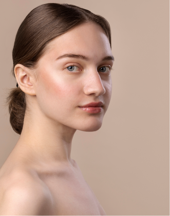 A portrait of a young woman with clear, radiant skin, her hair neatly tied back. She has a serene expression and is looking slightly to the side after getting a Hydralight Facial